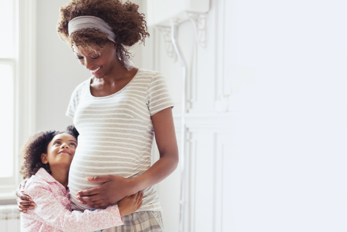 Young daughter hugging her pregnant mother