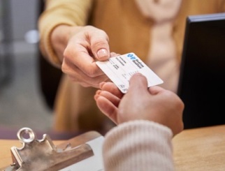 A woman handing a BCBS ID card to a medical office worker.